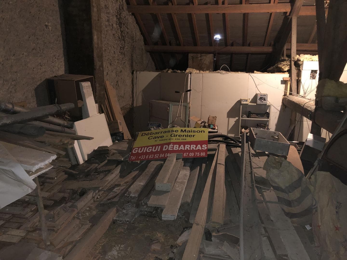 Combles encombrés de planches et de mobilier avant le débarras